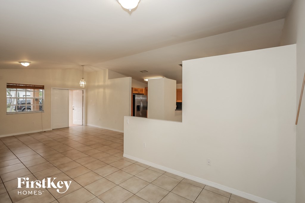 an empty living room with a white wall and tile floor