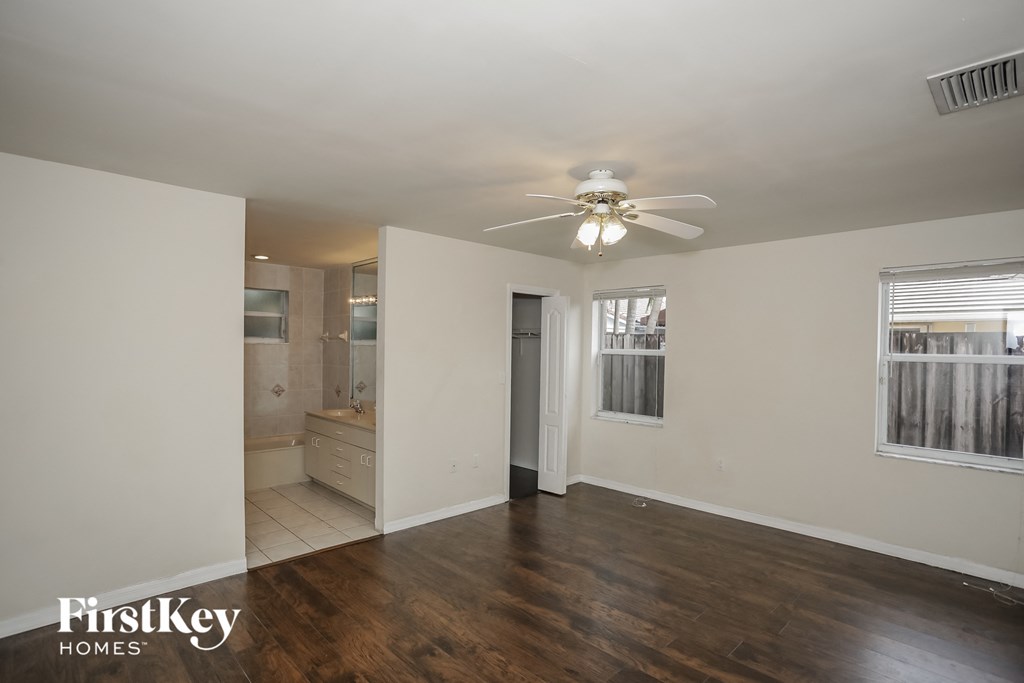 an empty living room with a ceiling fan and a bathroom