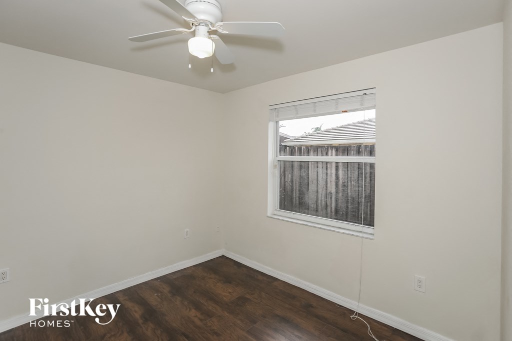 a bedroom with white walls and a ceiling fan and a window