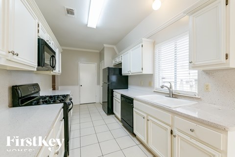 A kitchen with white cabinets and black appliances.