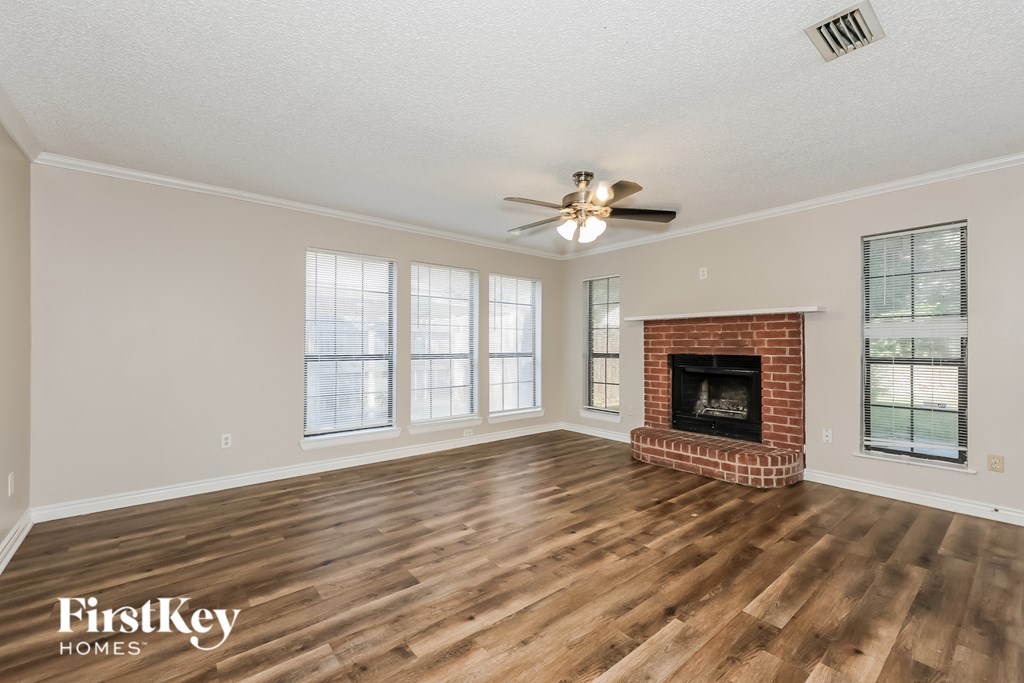 A spacious room with a fireplace and a ceiling fan.
