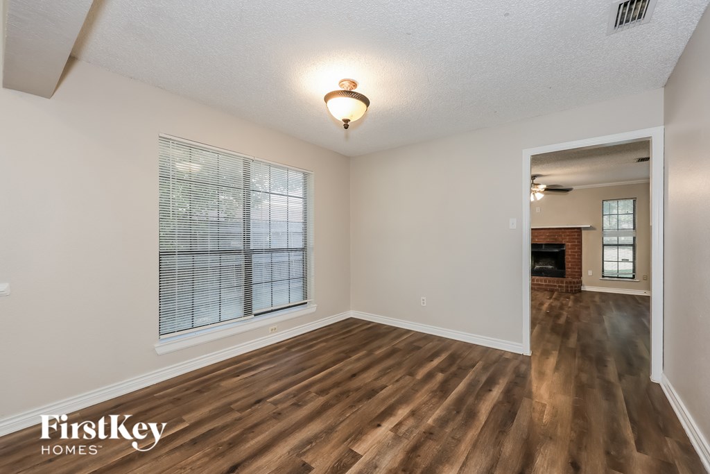 A room with wooden floors and a window with blinds.