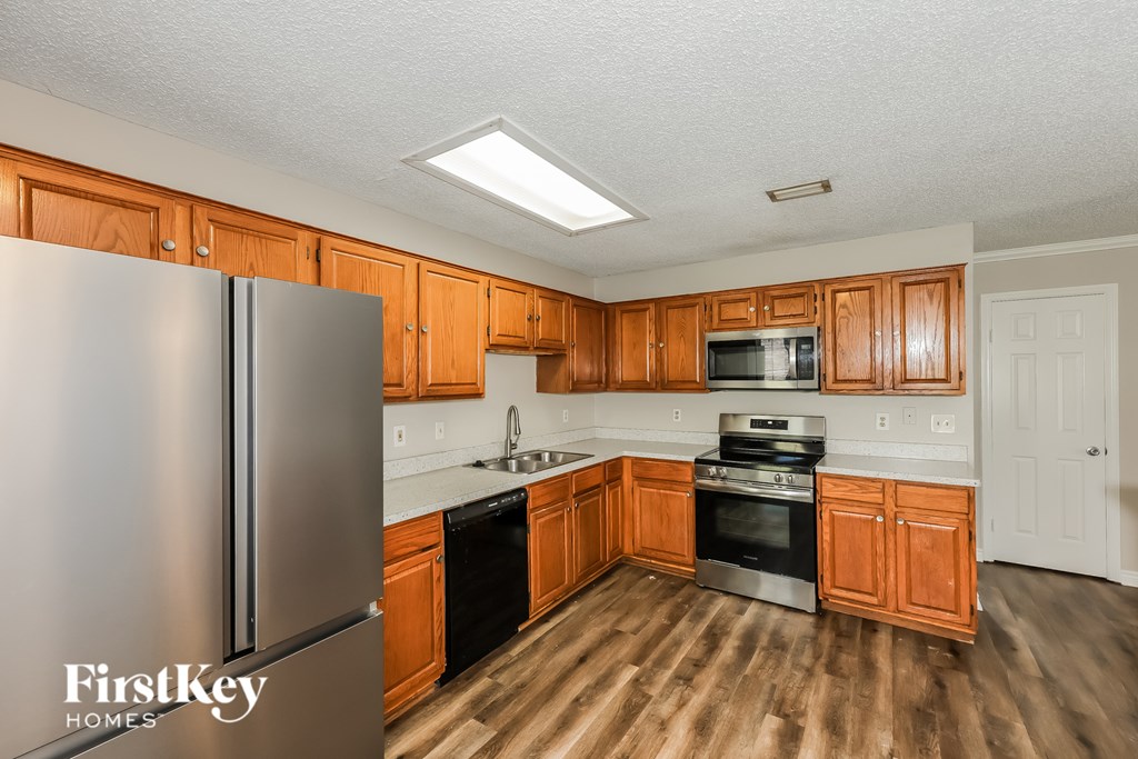 A kitchen with wooden cabinets and a stainless steel refrigerator.