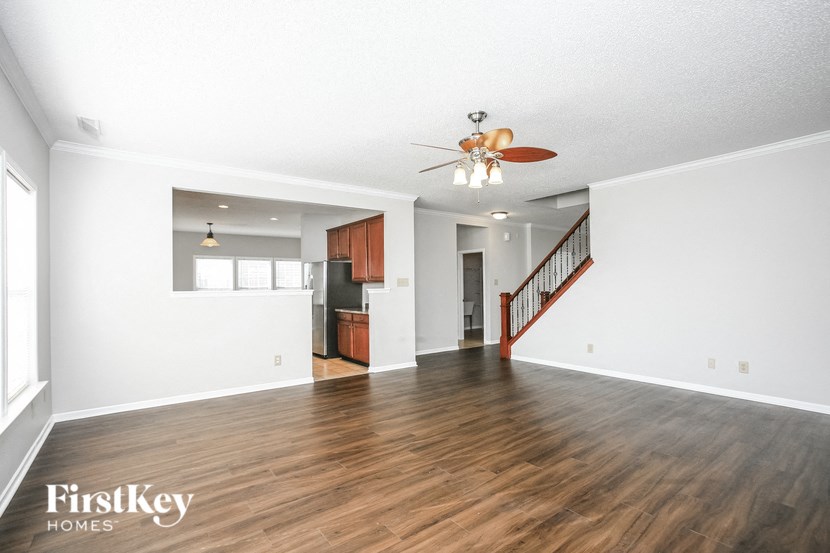 an empty living room with white walls and a ceiling fan
