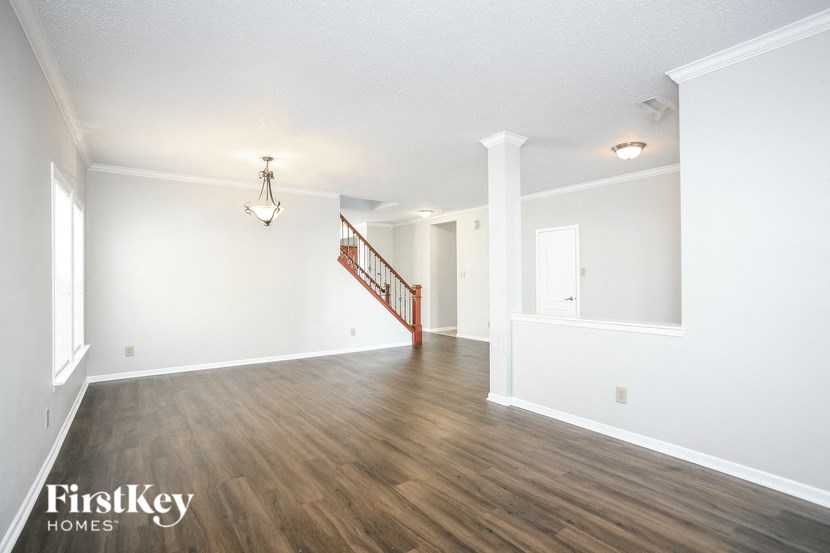a living room with white walls and wood floors and a staircase