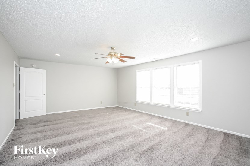 an empty living room with a ceiling fan