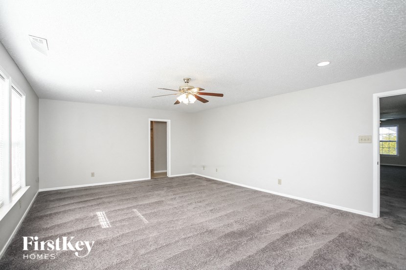 a living room with carpet and a ceiling fan