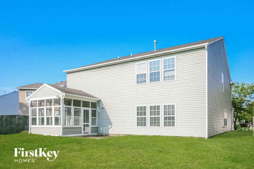 the outside of a white house with a conservatory and a green yard
