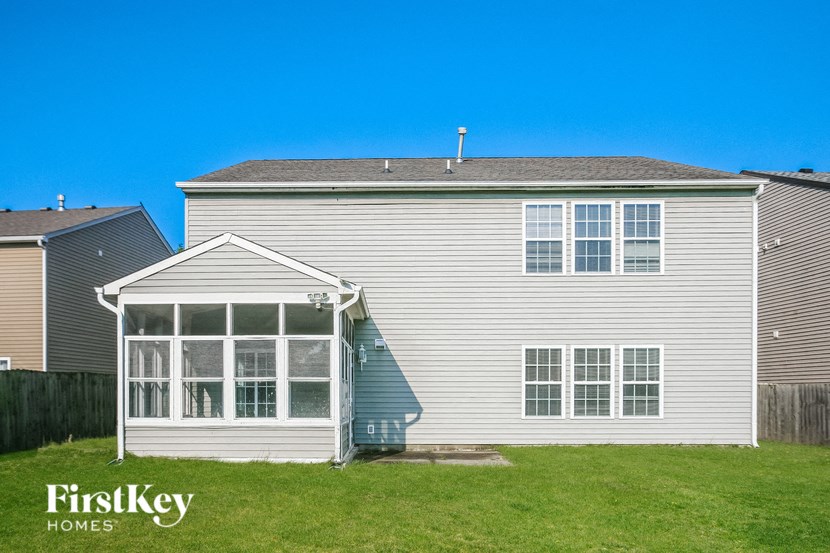 the back of a white house with a porch and a lawn