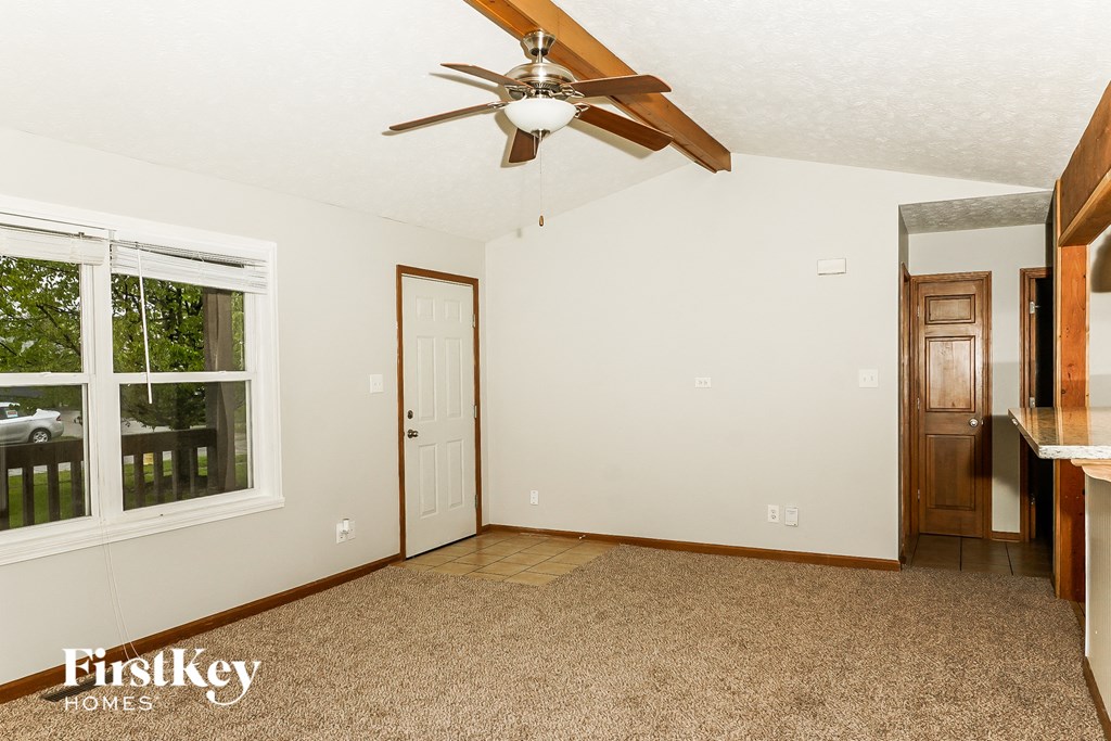 an empty living room with a ceiling fan and a window