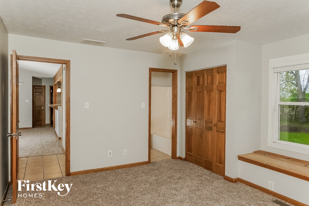 the master bedroom has a ceiling fan and a door to the ensuite bathroom