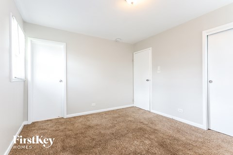 a bedroom with white walls and carpet and two doors