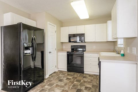 A kitchen with a black refrigerator and white cabinets.
