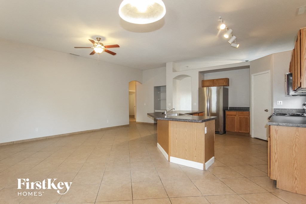 an open kitchen and living room with an island and a ceiling fan