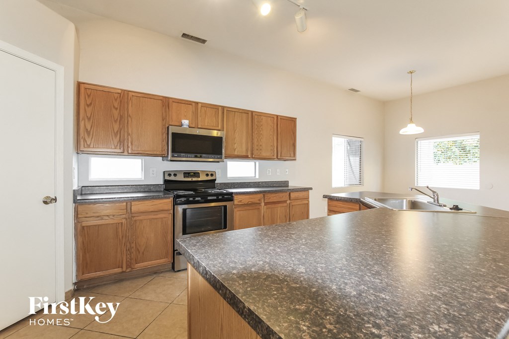 an updated kitchen with granite counter tops and wooden cabinets