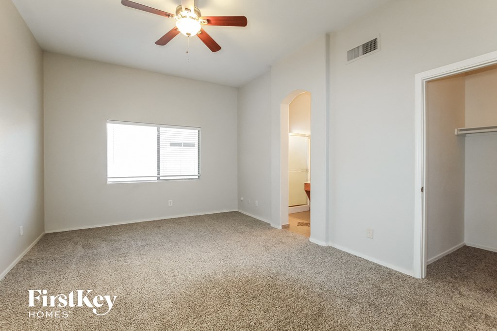 an empty living room with a ceiling fan and a closet