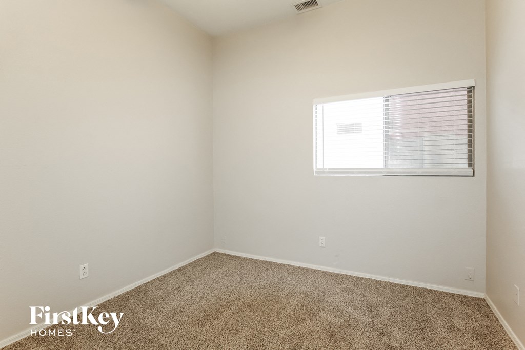a bedroom with a window and a carpeted floor