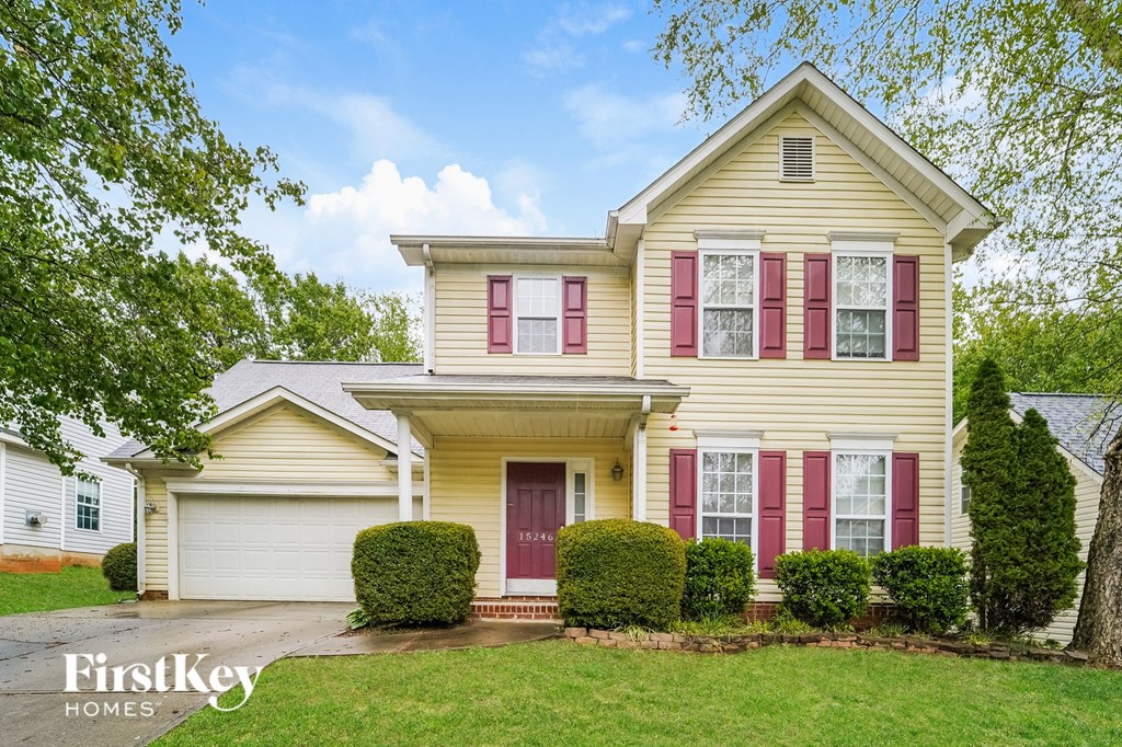 a yellow house with red shutters and a white garage