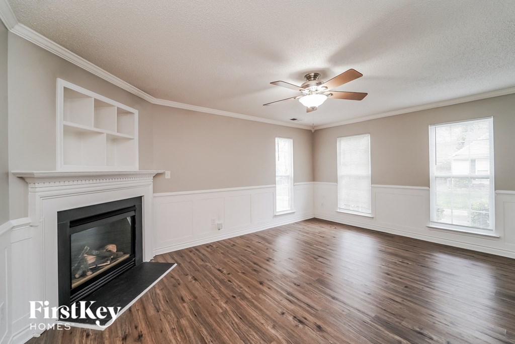 an empty living room with a fireplace and a ceiling fan