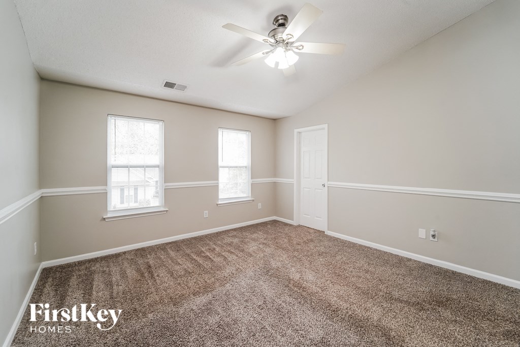 a spacious living room with carpet and a ceiling fan