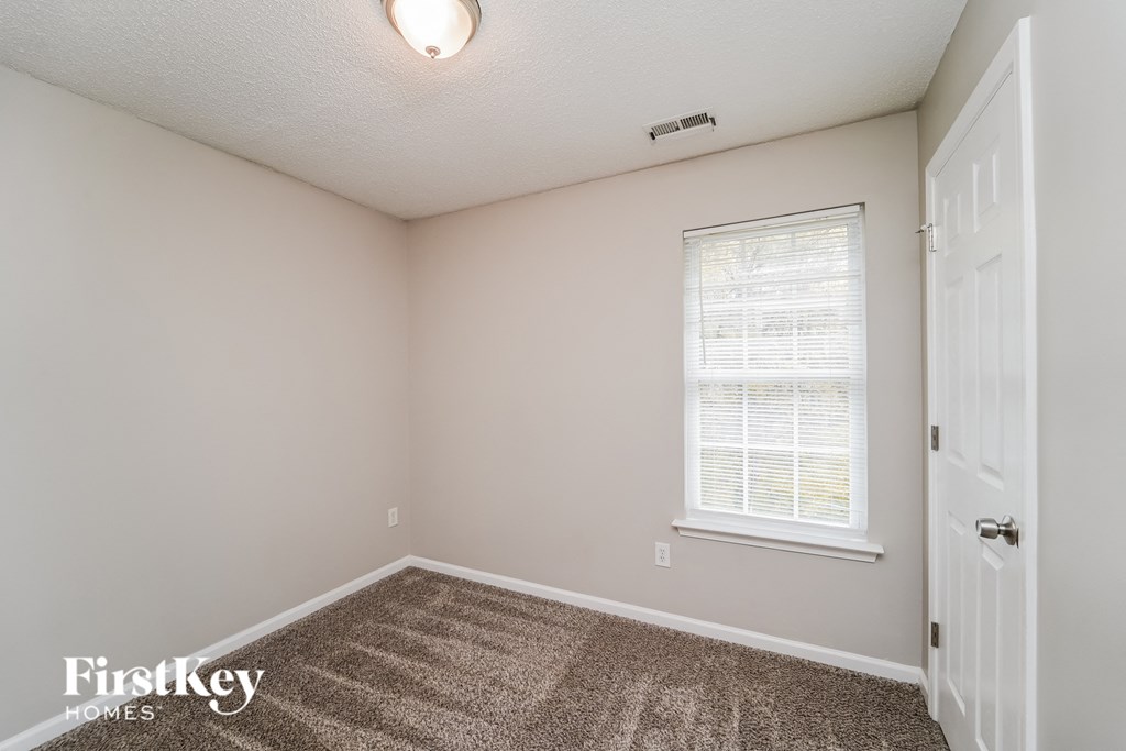 the bedroom of an apartment with carpeted flooring and a window