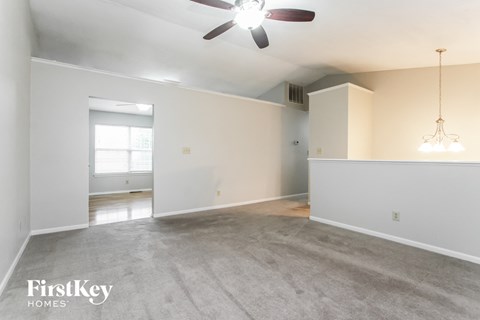 the living room and dining room of an empty house with a ceiling fan