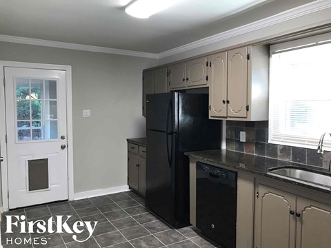 A kitchen with a black fridge and cabinets.