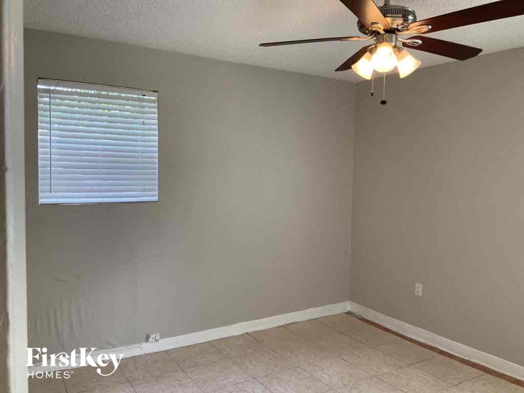 A room with a ceiling fan and a window with blinds.