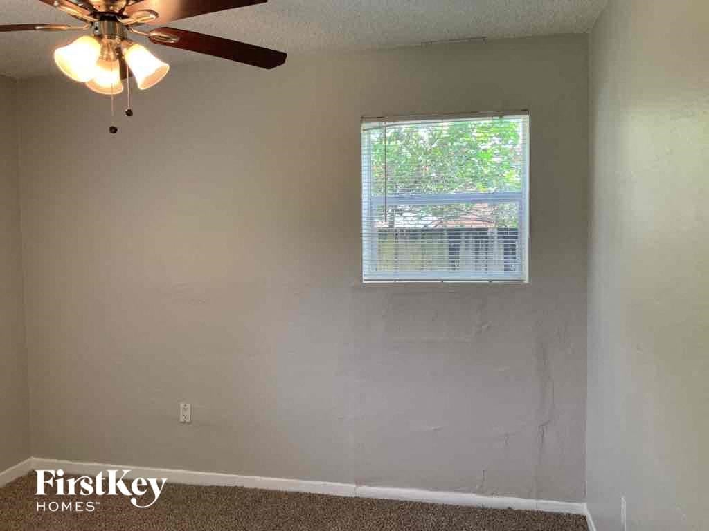 A room with a ceiling fan and a window with blinds.