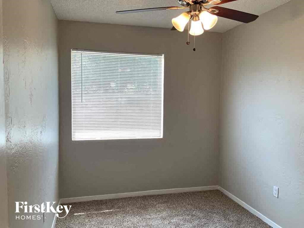 A room with a ceiling fan and a window with blinds.