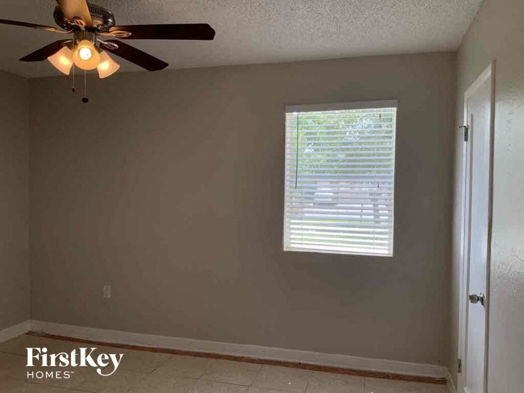A room with a ceiling fan and a window with blinds.