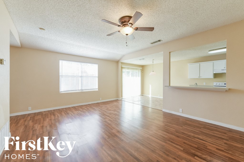 A spacious room with wood flooring and a ceiling fan.