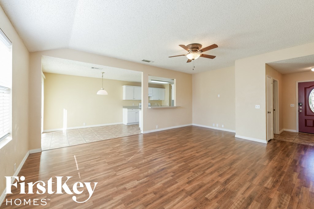 A spacious room with wooden floors and a ceiling fan.