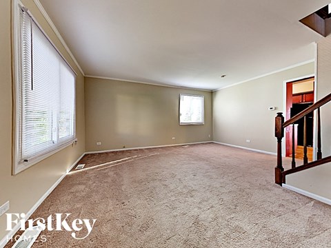 A room with a carpeted floor and a window with blinds.