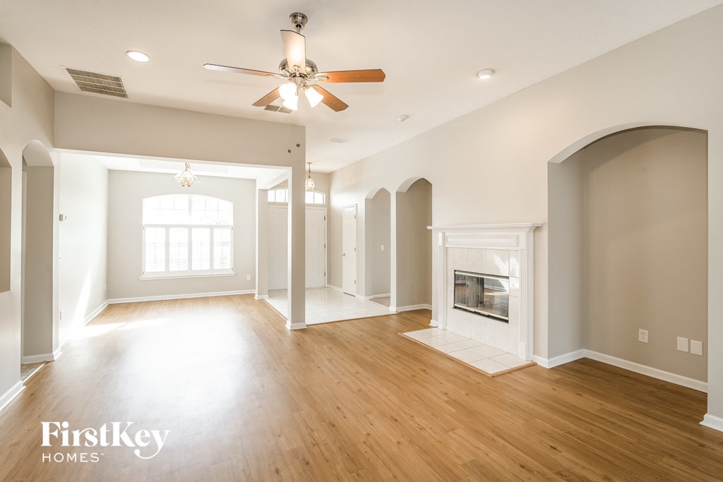 A spacious living room with wood floors and a fireplace.
