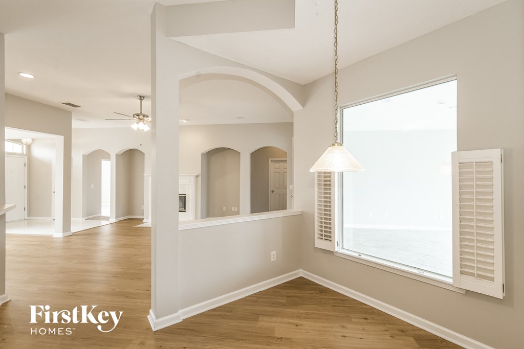 A well-lit, spacious room with wooden floors and arched doorways.