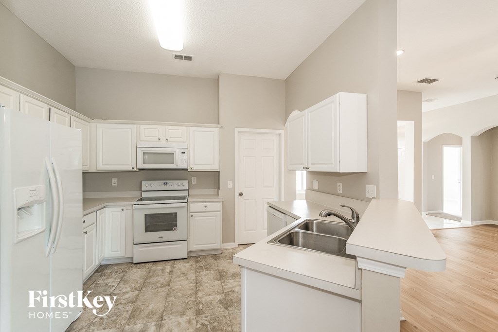 A kitchen with a refrigerator, sink, and cabinets.