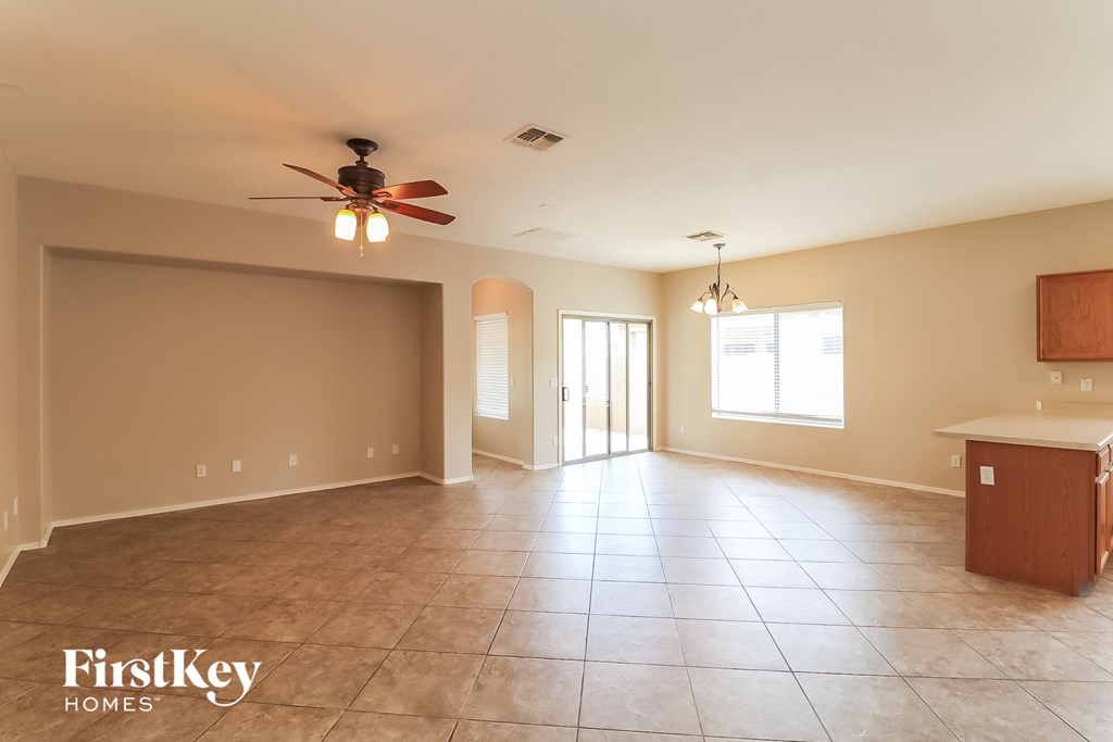A spacious room with a ceiling fan and a kitchenette.