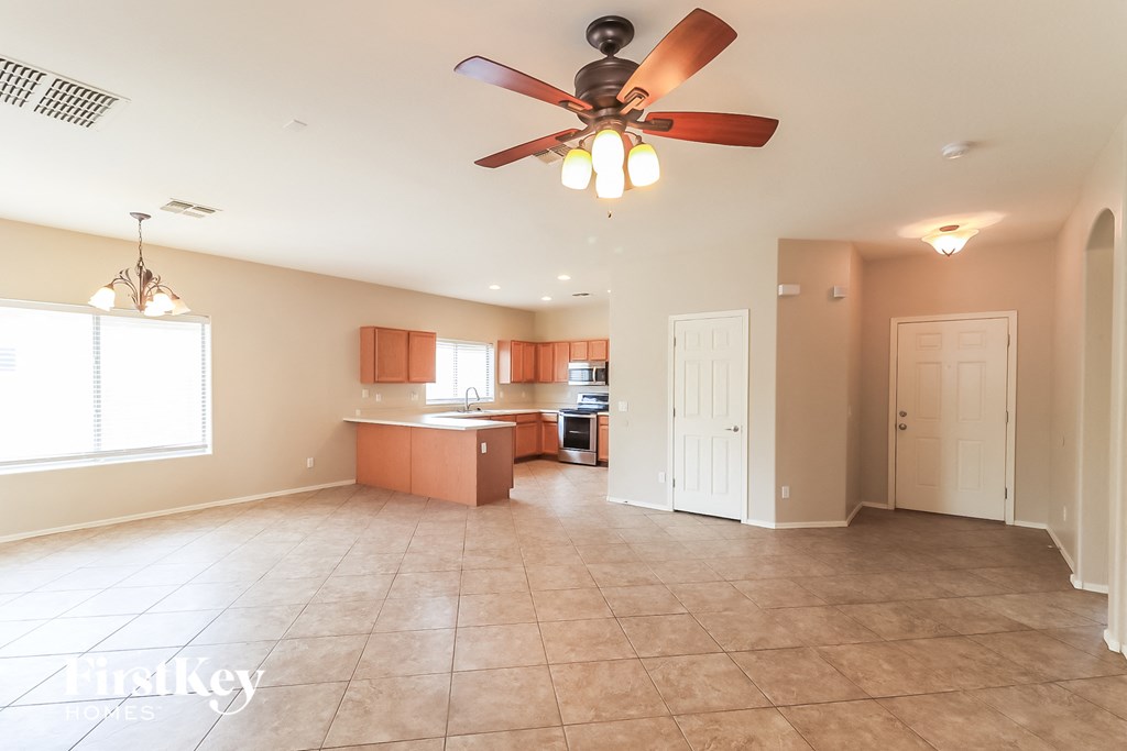 A spacious living room with a kitchen area in the background.