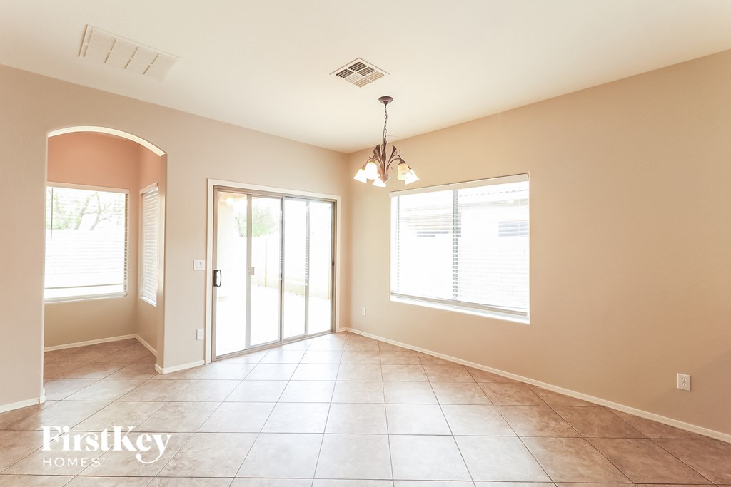 A spacious room with tile flooring and a chandelier hanging from the ceiling.