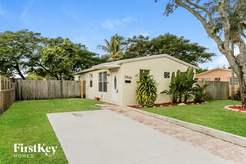 a white house with a yard and a sidewalk and a fence