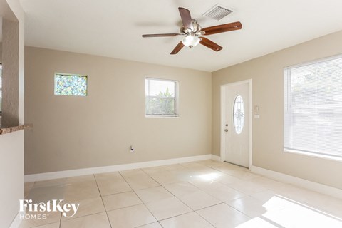 an empty living room with a ceiling fan and tiled floors