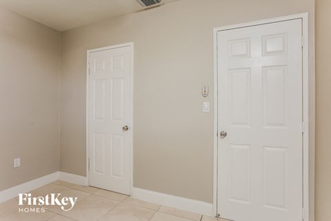 a bedroom with two white doors and a tiled floor