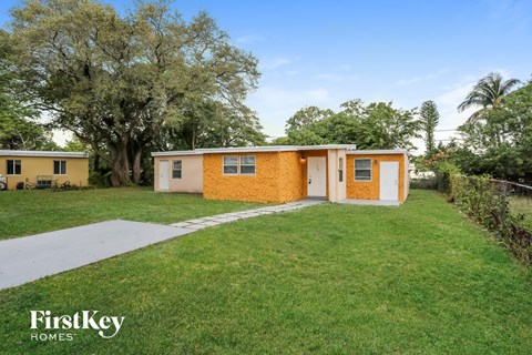 a small yellow house with a yard and a sidewalk