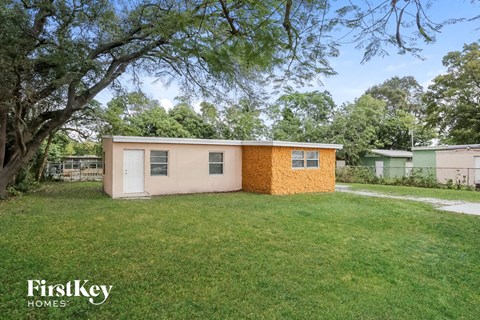 a small house with a grassy yard and a tree