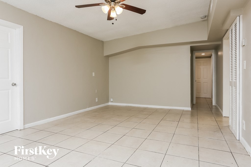 an empty living room with a ceiling fan and tiled floor