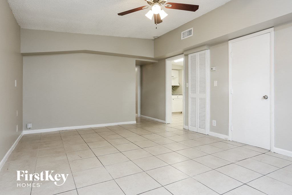 an empty living room with a ceiling fan and a tiled floor
