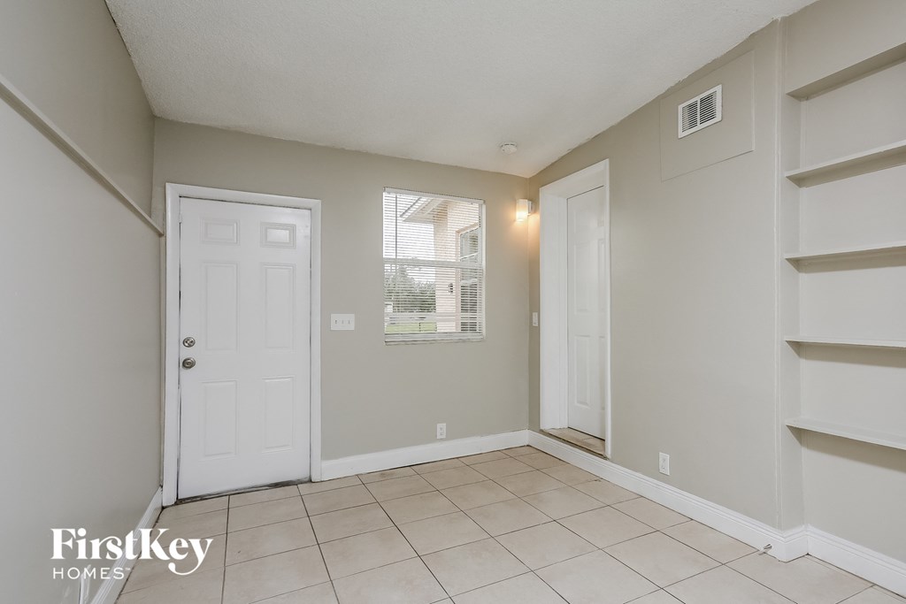 the living room and entryway of an empty house with a white door