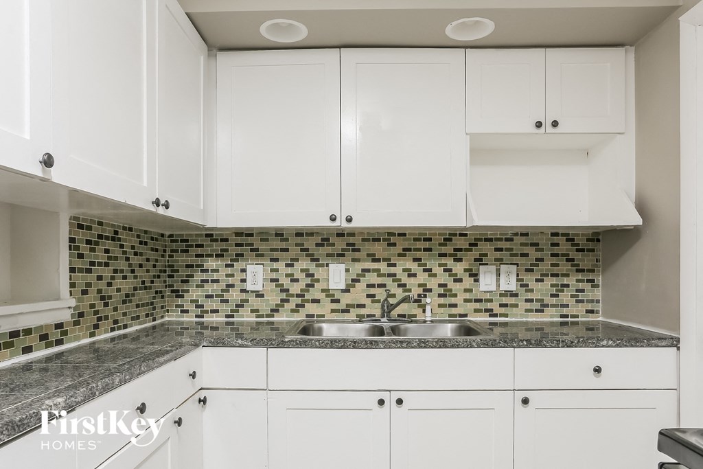 a white kitchen with white cabinets and a sink