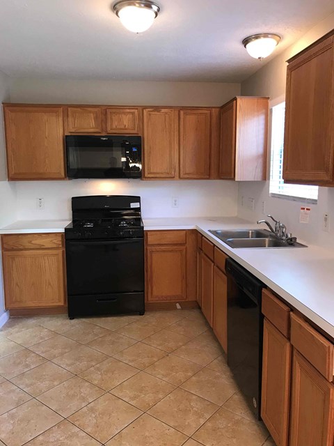 A kitchen with wooden cabinets and black appliances.
